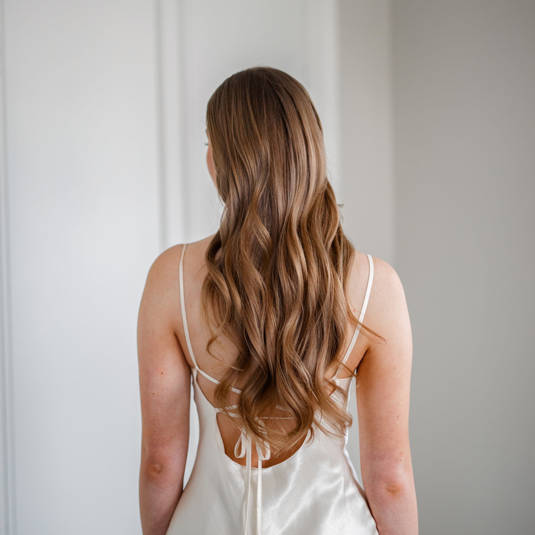 Your Curl Wand resultat med Molimenti. Kvinna visar upp sitt stylade hår efter användning av Your Curl Wand från Molimenti. Håret är format i mjuka, glansiga vågor med naturlig volym och en hälsosam finish. Bilden fångar resultatet i naturligt ljus och framhäver stylingens effekt.