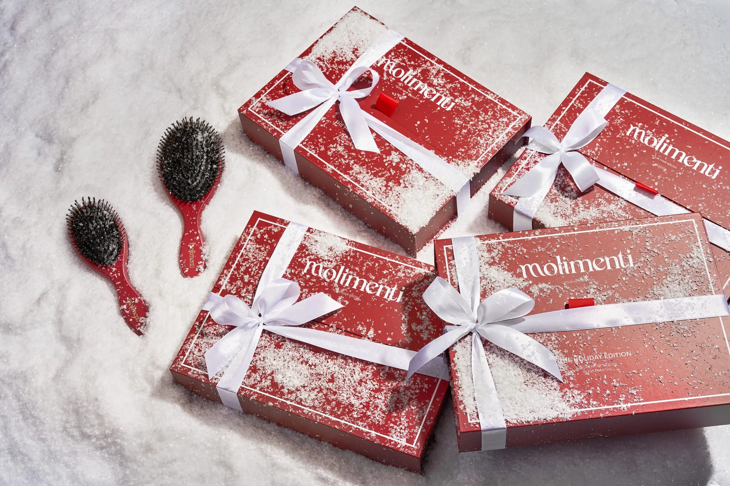 Röda presentaskar från Molimenti Holiday Collection Rosso med Your Hair Brush, inslagna i snöliknande miljö – perfekt julklapp för henne som älskar hårvård.